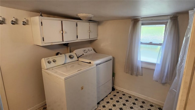 laundry room with baseboards, light floors, cabinet space, and washing machine and clothes dryer