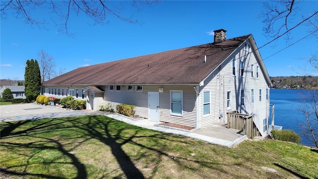 back of property with a lawn, a chimney, and a shingled roof