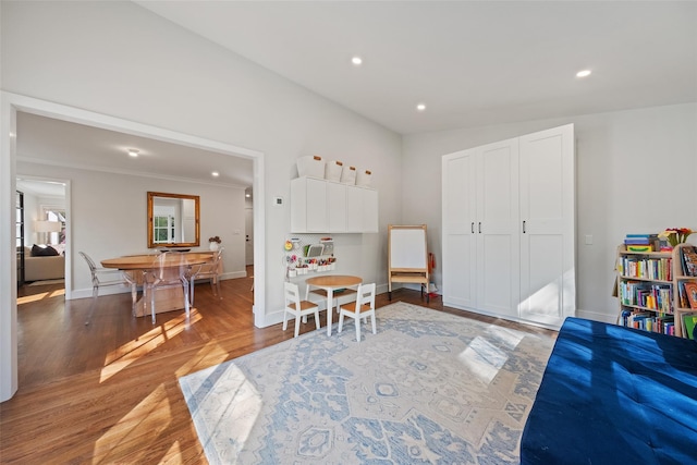 recreation room with recessed lighting, ornamental molding, baseboards, and wood finished floors