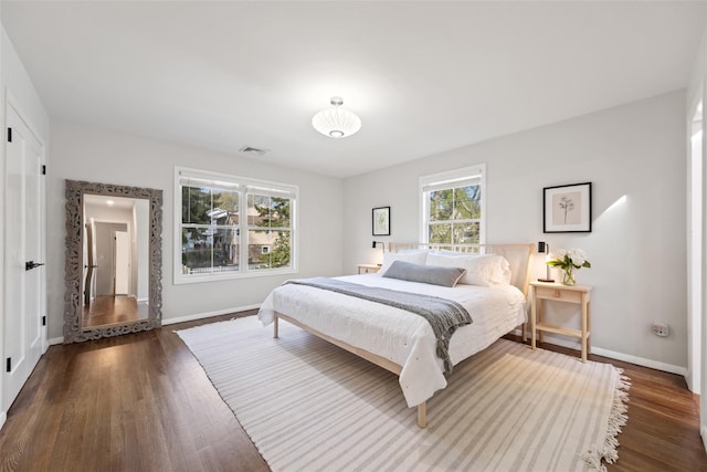 bedroom featuring baseboards, wood finished floors, and visible vents