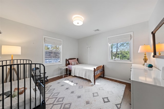 bedroom featuring visible vents, wood finished floors, and multiple windows
