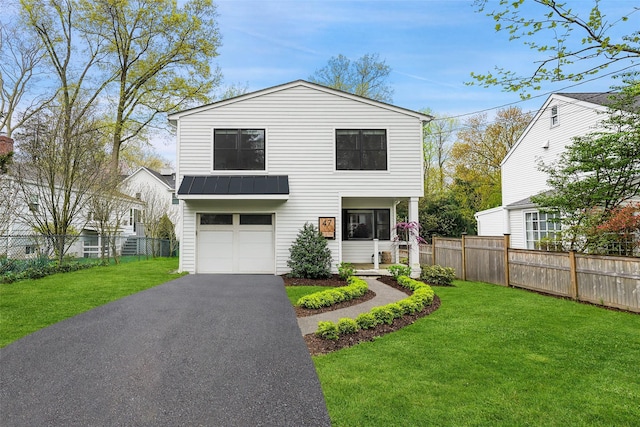 view of front of property featuring fence, a garage, a front yard, a standing seam roof, and driveway