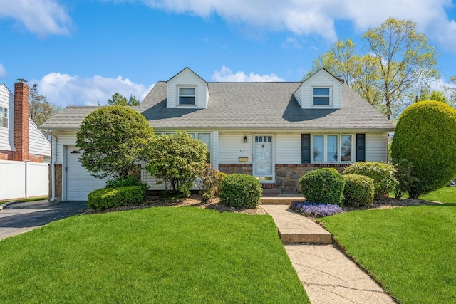 cape cod house with a shingled roof, fence, an attached garage, and a front yard