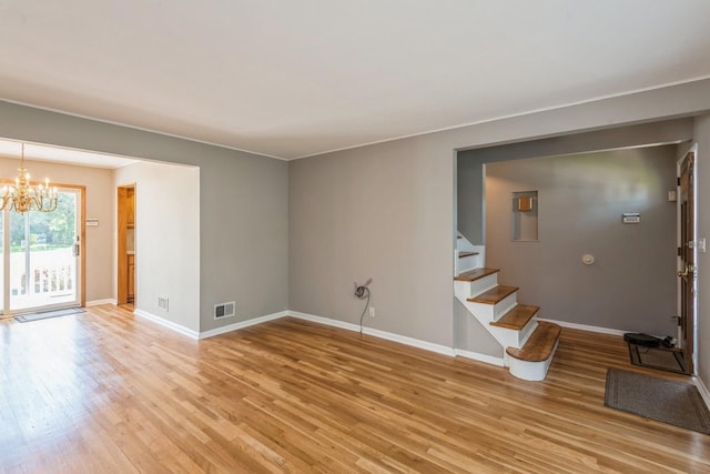 unfurnished living room featuring visible vents, an inviting chandelier, baseboards, stairway, and light wood-type flooring