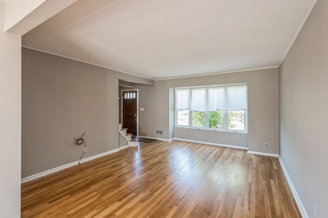 spare room featuring stairs, baseboards, ornamental molding, and wood finished floors