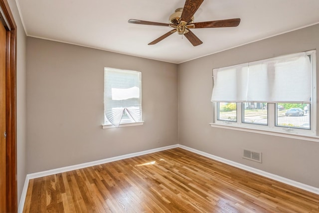 spare room featuring visible vents, ornamental molding, wood finished floors, baseboards, and ceiling fan