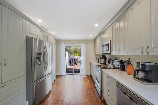 kitchen featuring appliances with stainless steel finishes, light countertops, baseboards, recessed lighting, and dark wood-type flooring