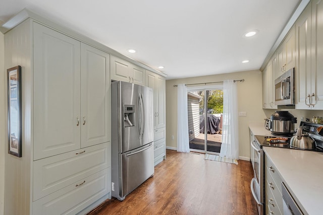 kitchen with light countertops, baseboards, stainless steel appliances, recessed lighting, and dark wood-type flooring