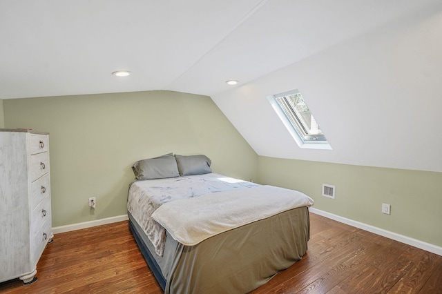 bedroom with visible vents, baseboards, lofted ceiling with skylight, and wood finished floors