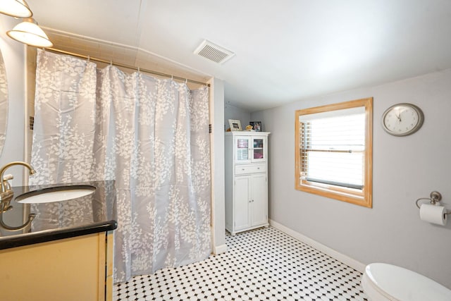 bathroom featuring visible vents, vanity, baseboards, tile patterned floors, and vaulted ceiling