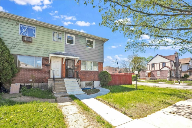 townhome / multi-family property with brick siding, fence, and a front yard