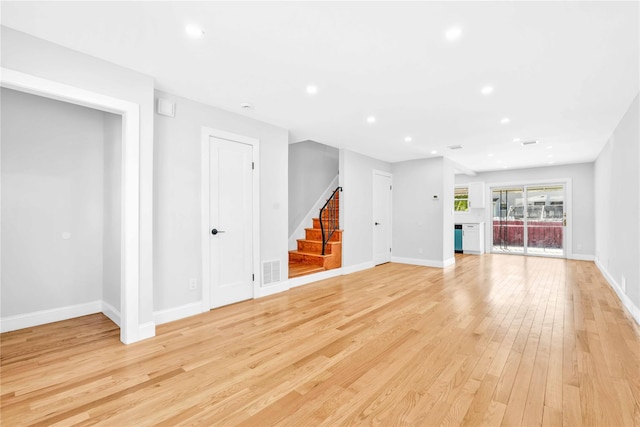 unfurnished living room with visible vents, light wood-style floors, baseboards, stairway, and recessed lighting