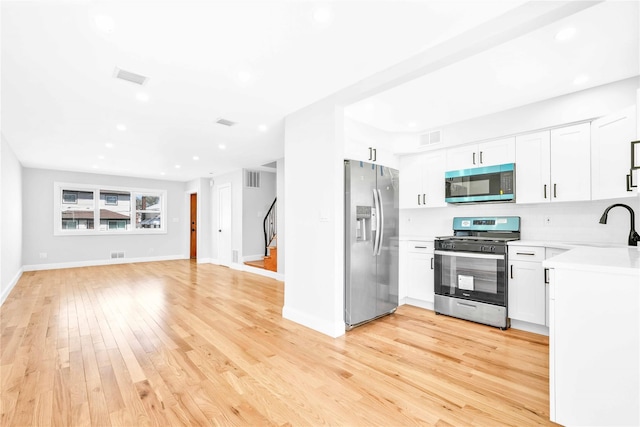kitchen with visible vents, appliances with stainless steel finishes, light countertops, a sink, and light wood finished floors