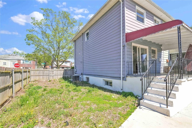 view of property exterior with fence and central AC unit