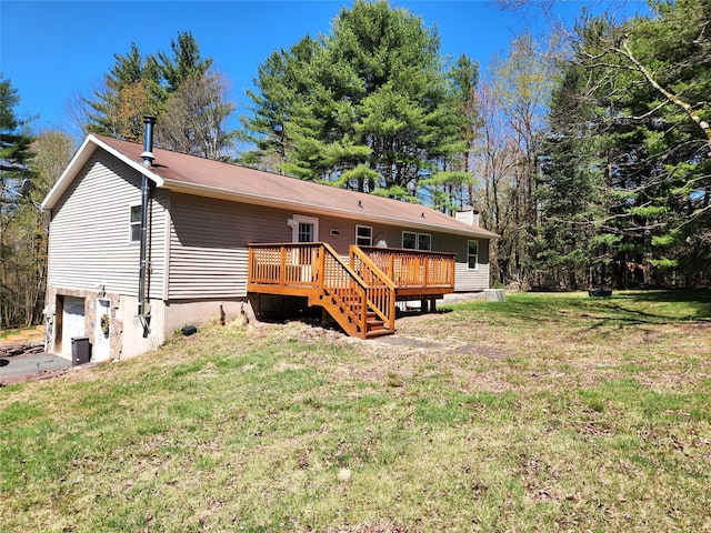 back of house featuring a yard, an attached garage, and a wooden deck