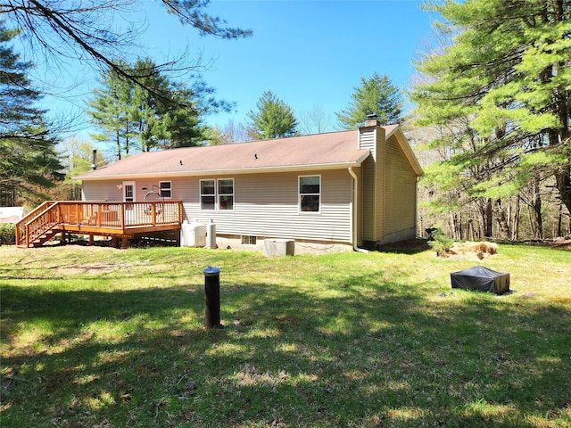 rear view of house featuring a lawn, a chimney, and a deck