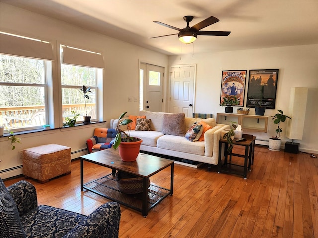 living area featuring a ceiling fan, baseboard heating, and hardwood / wood-style floors