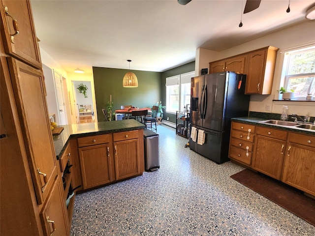 kitchen with brown cabinetry, a sink, and refrigerator with ice dispenser