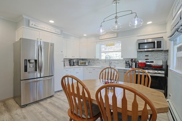 kitchen with decorative backsplash, baseboard heating, light countertops, a sink, and stainless steel appliances