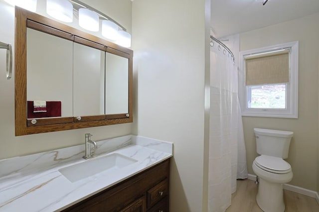 full bath with toilet, baseboards, wood finished floors, and vanity