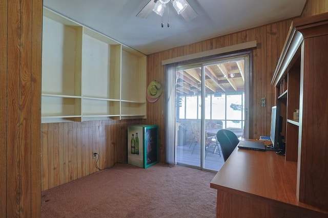 unfurnished office with carpet, a ceiling fan, and wood walls