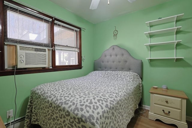 bedroom featuring baseboards, ceiling fan, wood finished floors, and a baseboard radiator