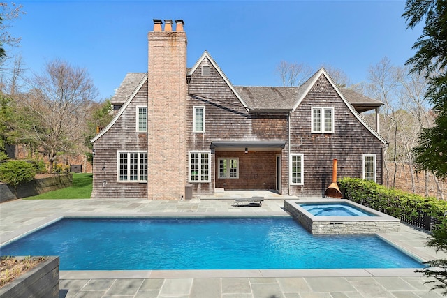 back of house featuring a fenced in pool, an in ground hot tub, a chimney, and a patio area