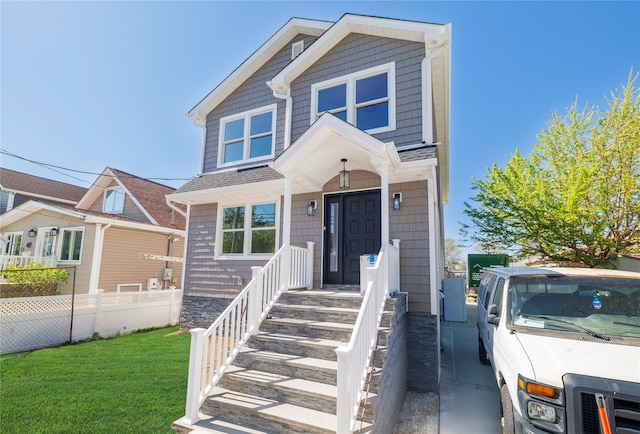 view of front of house featuring fence, a shingled roof, and a front lawn