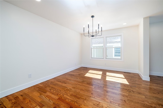 unfurnished room featuring visible vents, wood finished floors, baseboards, a notable chandelier, and recessed lighting