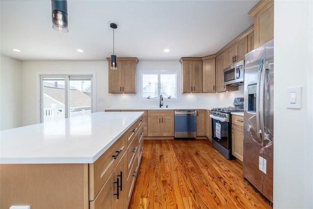 kitchen with a sink, appliances with stainless steel finishes, plenty of natural light, and wood finished floors