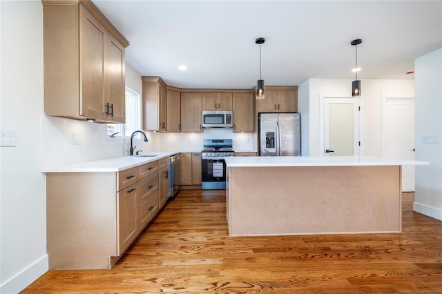 kitchen with a sink, appliances with stainless steel finishes, baseboards, and light wood finished floors