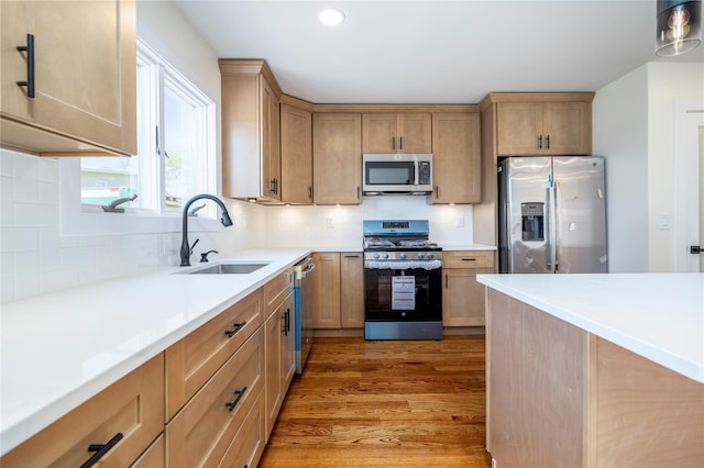 kitchen featuring a sink, tasteful backsplash, stainless steel appliances, and light wood finished floors