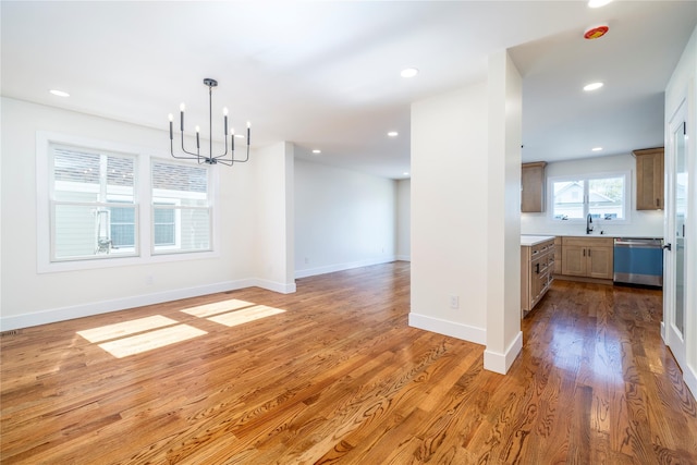 unfurnished dining area with an inviting chandelier, a sink, recessed lighting, and light wood-type flooring
