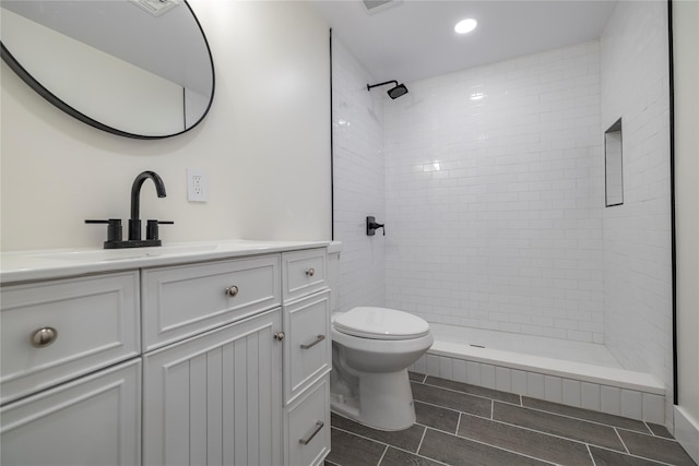 full bath with vanity, recessed lighting, a tile shower, and toilet