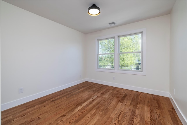 unfurnished room featuring visible vents, baseboards, and wood finished floors