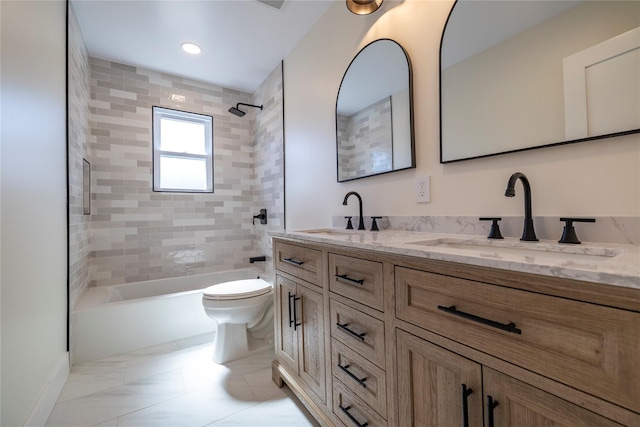 bathroom with double vanity, a sink, shower / bathtub combination, and toilet