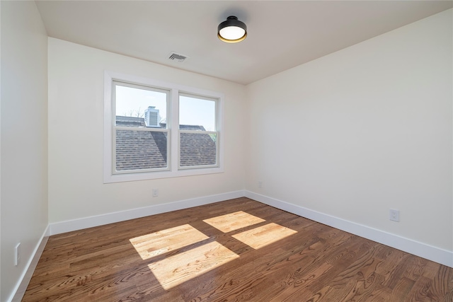 empty room with baseboards, wood finished floors, and visible vents