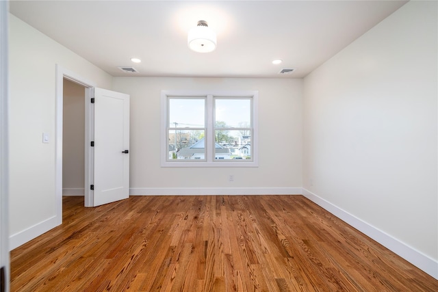 unfurnished room with baseboards, visible vents, and wood finished floors