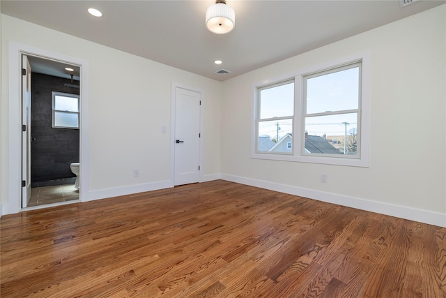 empty room with recessed lighting, baseboards, visible vents, and wood finished floors