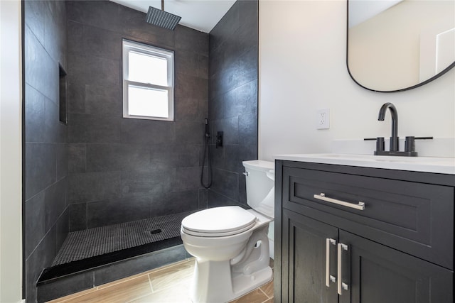 full bath featuring toilet, tiled shower, and vanity