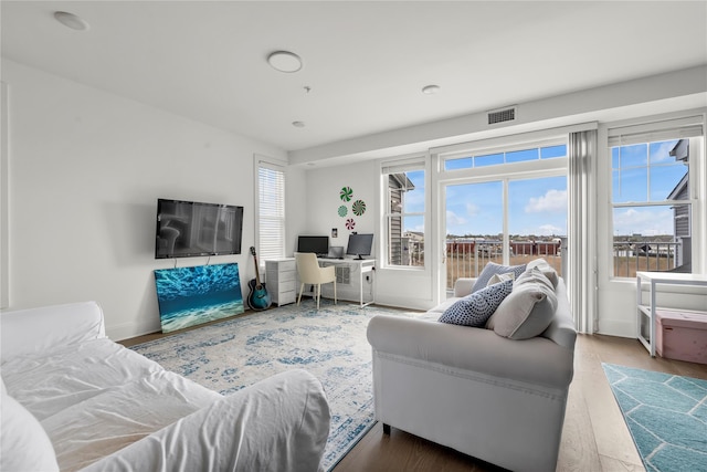 living area with baseboards, visible vents, and wood finished floors