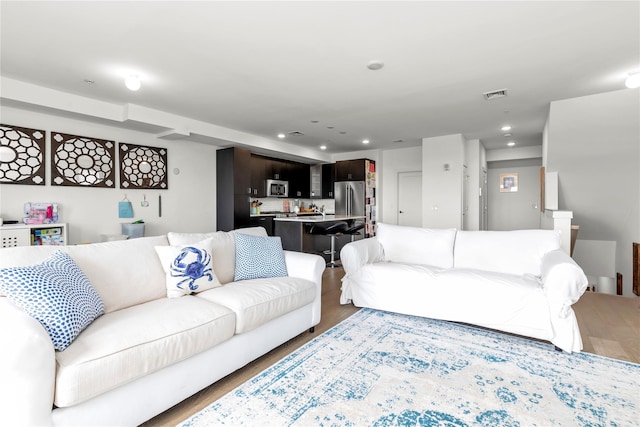 living room with visible vents, recessed lighting, and wood finished floors