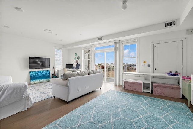 living room featuring visible vents, plenty of natural light, and wood finished floors