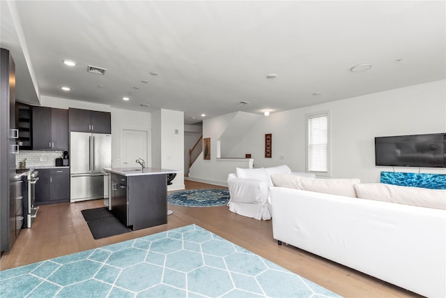 living area featuring light wood-style floors, recessed lighting, stairs, and visible vents