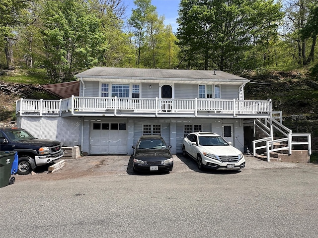 view of front of house with an attached garage, stairway, and aphalt driveway