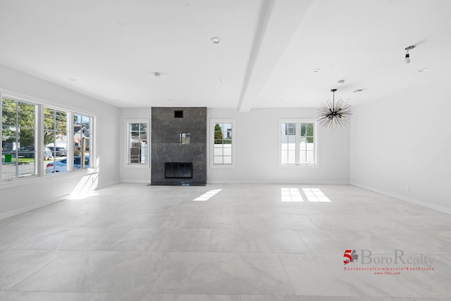 unfurnished living room with baseboards, a fireplace, and beam ceiling