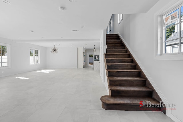 stairway featuring baseboards and visible vents