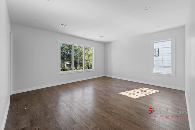 unfurnished room with baseboards, visible vents, and dark wood-type flooring