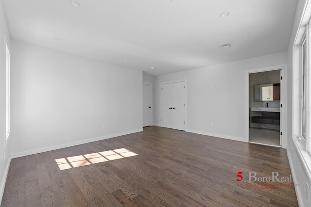 empty room featuring baseboards, wood finished floors, and visible vents