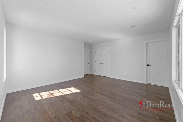 unfurnished room featuring baseboards, visible vents, and wood finished floors
